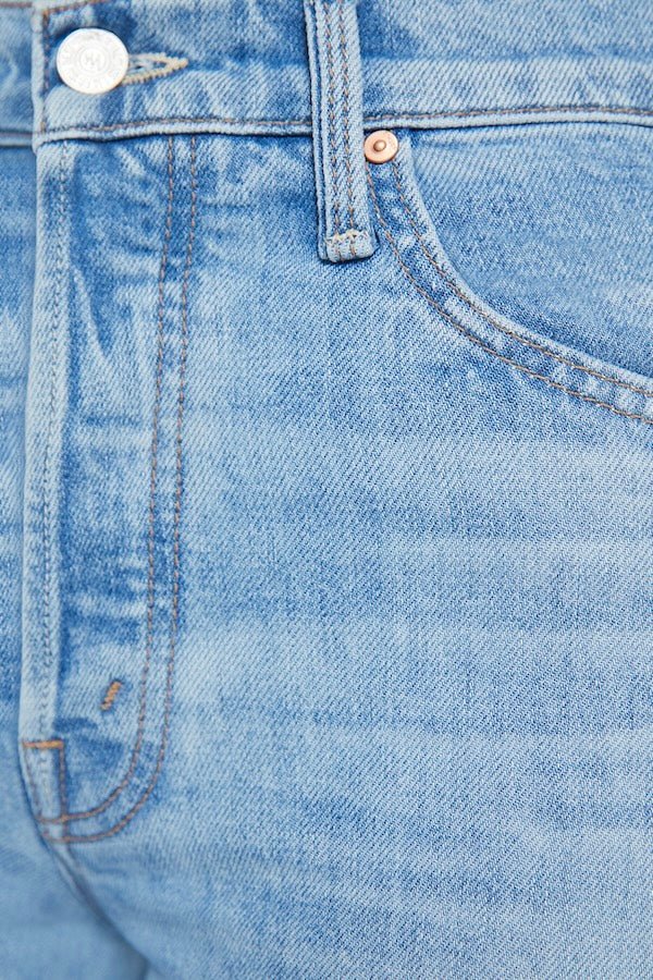 The Tomcat Roller Skimp Puzzled by MOTHER, trendy high-waisted wide-leg jeans with a button fly and light blue wash. Perfect for a relaxed, stylish look with whiskering and fading at the knees.