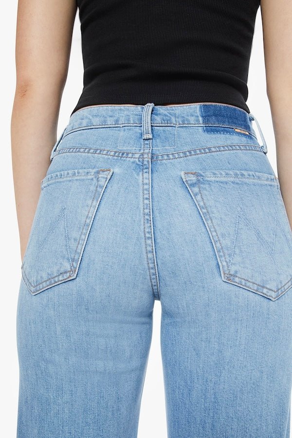 The Tomcat Roller Skimp Puzzled by MOTHER, trendy high-waisted wide-leg jeans with a button fly and light blue wash. Perfect for a relaxed, stylish look with whiskering and fading at the knees.