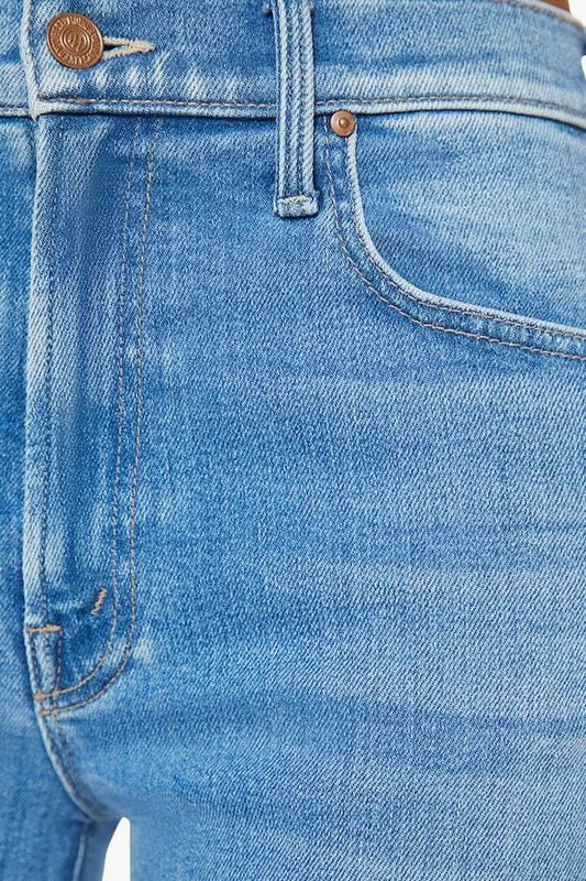 The Rambler Zip Flood Read Between The Lines by MOTHER, trendy high-waisted jeans with a wide straight leg, whiskering, and fading. Perfect for a stylish and comfortable look in a mid-blue wash.