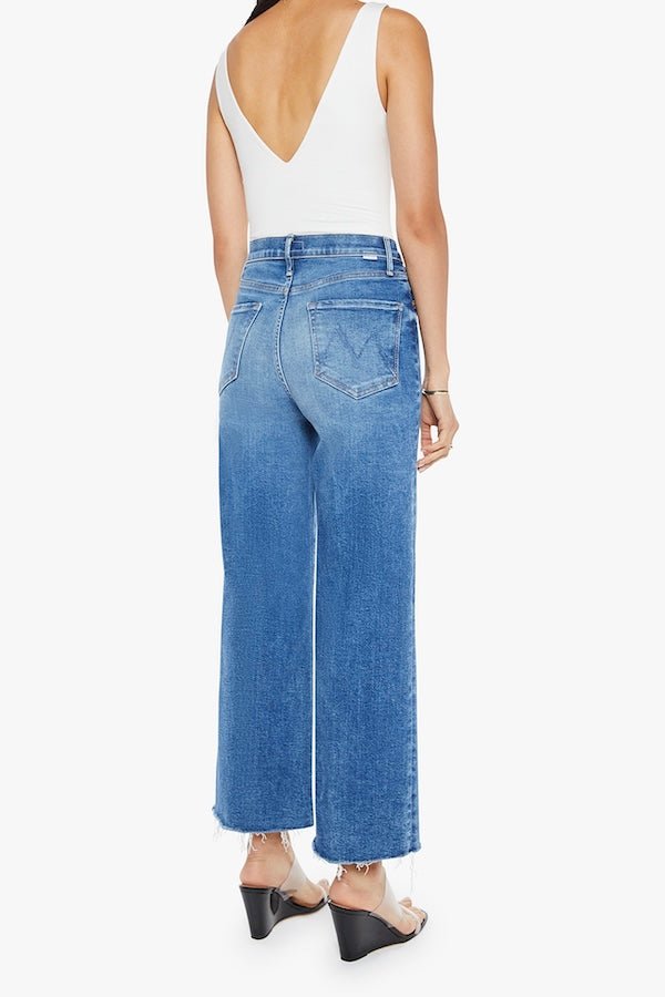 The Maven Ankle Fray Bitchin' by MOTHER, trendy high-rise jeans with a loose fit, wide leg, and frayed hem. Perfect for a relaxed, stylish look with mid-blue whiskering and fading at the knee.