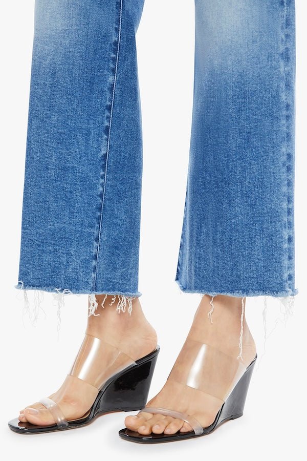 The Maven Ankle Fray Bitchin' by MOTHER, trendy high-rise jeans with a loose fit, wide leg, and frayed hem. Perfect for a relaxed, stylish look with mid-blue whiskering and fading at the knee.