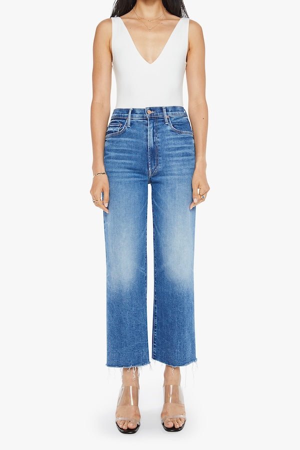 The Maven Ankle Fray Bitchin' by MOTHER, trendy high-rise jeans with a loose fit, wide leg, and frayed hem. Perfect for a relaxed, stylish look with mid-blue whiskering and fading at the knee.