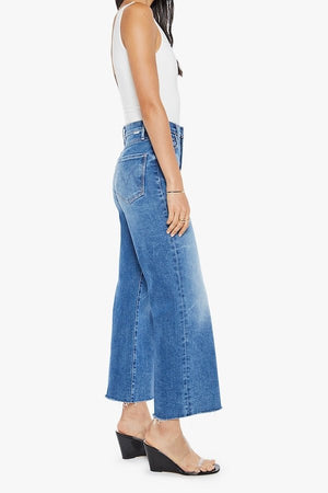 The Maven Ankle Fray Bitchin' by MOTHER, trendy high-rise jeans with a loose fit, wide leg, and frayed hem. Perfect for a relaxed, stylish look with mid-blue whiskering and fading at the knee.