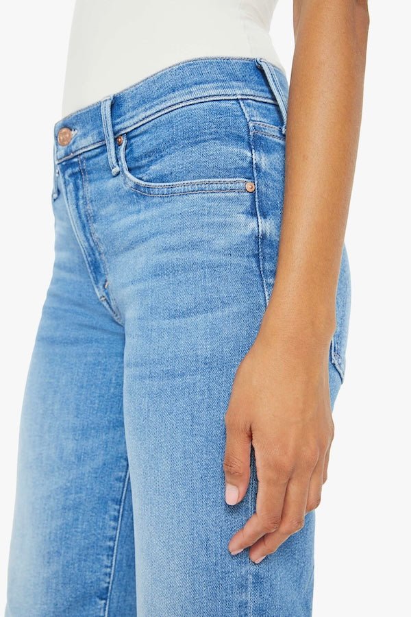The Mid Rise Zip Rambler Ankle Out Of The Blue by MOTHER, trendy mid-rise jeans with a wide straight leg and ankle-length inseam. Perfect for a relaxed, stylish look with whiskering and fading at the knee.