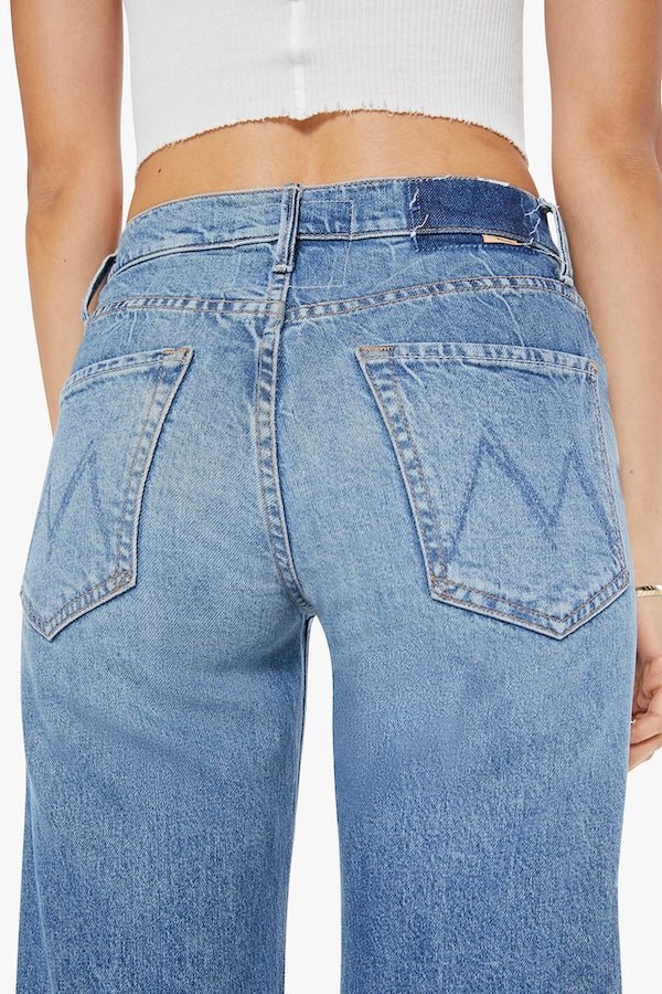 The Mid Rise Tunnel Vision Sneak I'm A Winner by MOTHER, trendy mid-rise jeans with a loose straight leg, featuring whiskering and fading at the knees. Perfect for a relaxed yet stylish look in a semi-rigid denim that softens with wear.