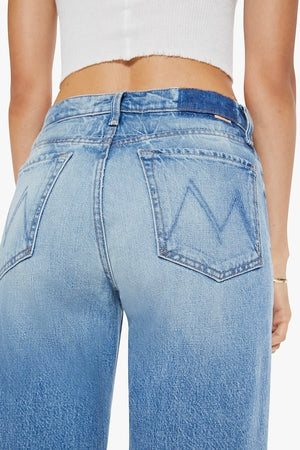 The Dodger Button Sneak Wipeout by MOTHER, trendy mid-blue jeans with a slouchy fit, loose straight leg, and a clean hem. Perfect for a relaxed look with whiskering and knee fading, made from rigid SUPERIOR denim.