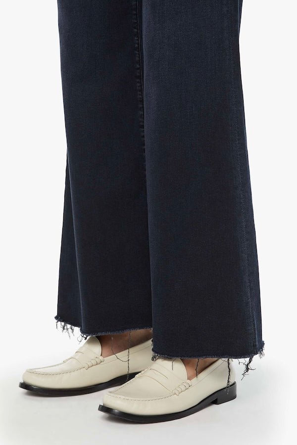 The Roller Fray Night In Venice by MOTHER, trendy high-waisted wide-leg jeans with a frayed hem and dark denim wash. Perfect for a relaxed yet stylish look with a 31-inch inseam and touch of stretch.