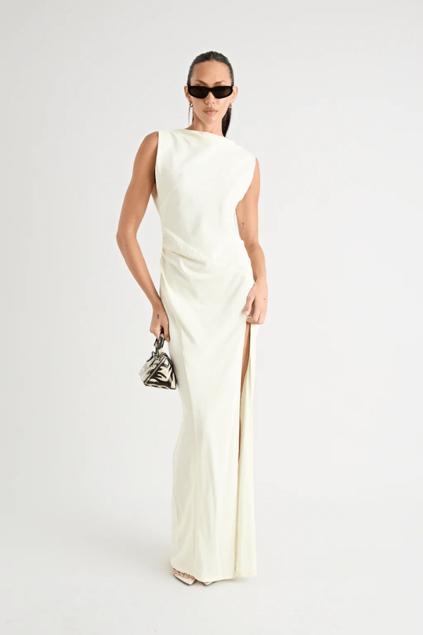Matia Gown Butter by Pfeiffer – A timeless maxi with a boat neckline, low back, and adjustable strap. Perfect for elegant events and special occasions.