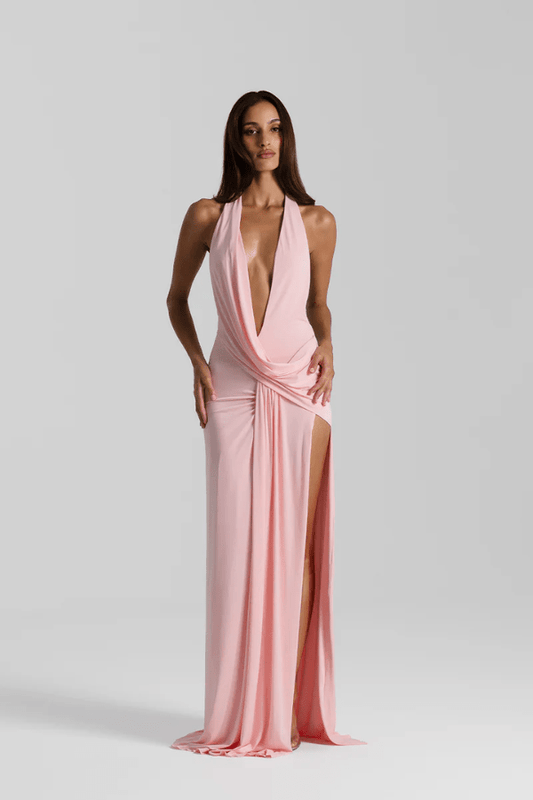 Winona Gown Blossom Pink by Natalie Rolt, elongated halter neckline, asymmetric draped bust overlay, open back, exaggerated side split, gathered waterfall skirt, full-length hem, elevated jersey. Dry clean only.