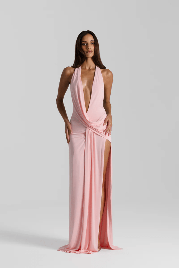 Winona Gown Blossom Pink by Natalie Rolt, elongated halter neckline, asymmetric draped bust overlay, open back, exaggerated side split, gathered waterfall skirt, full-length hem, elevated jersey. Dry clean only.