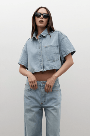Zara Cropped Denim Shirt Oakland Blue by Bayse, a trendy cropped denim shirt with a relaxed fit and snap-button front. Perfect for effortless styling, whether paired with high-waisted denim or layered over a fitted tank.