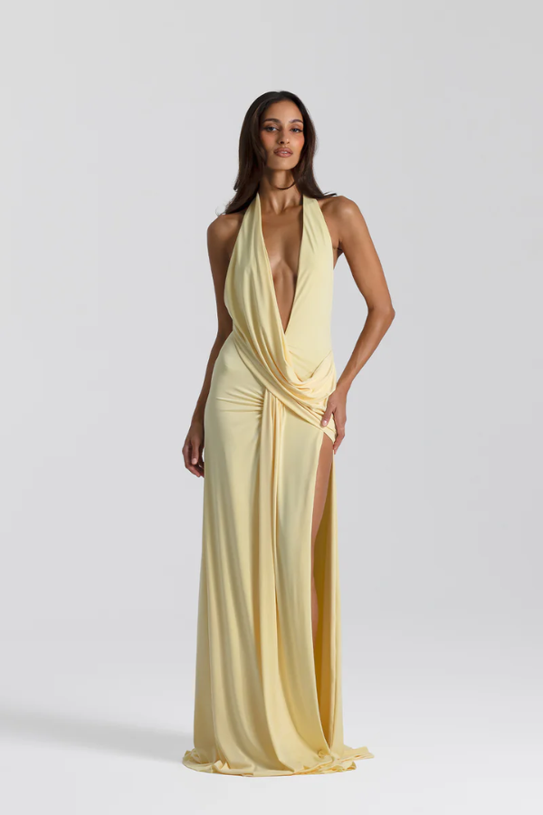 Winona Gown Lemon by Natalie Rolt, elongated halter neckline, asymmetric draped bust overlay, open back, exaggerated side split, gathered waterfall skirt, full-length hem, elevated jersey. Dry clean only.