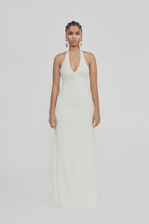 Roman Off White by Maygel Coronel – Elegant halter dress with deep V-neck, flattering ruching, and delicate 3D floral detail, perfect for refined events and celebrations.