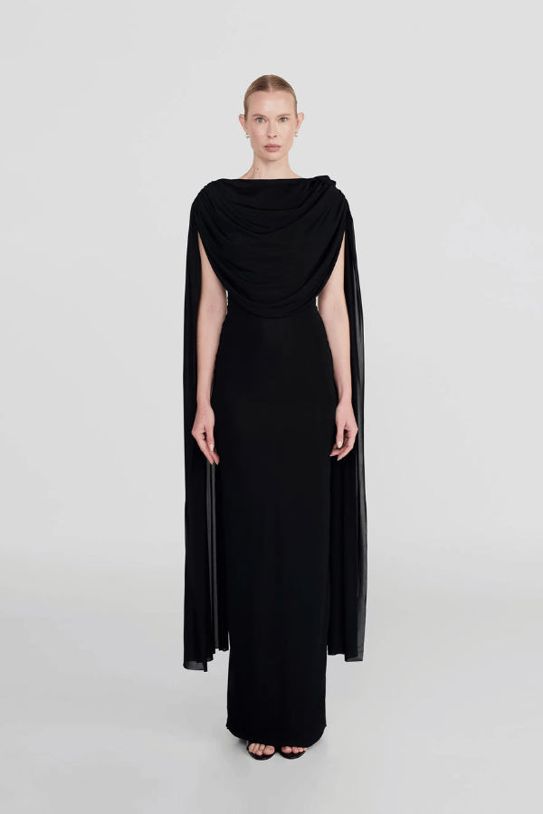 Batista Basalto by Maygel Coronel – An elegant long dress with a cowl scoop neckline, flowing shoulder sashes, and a sleek column silhouette, perfect for sophisticated evening events and making a timeless, statuesque statement.