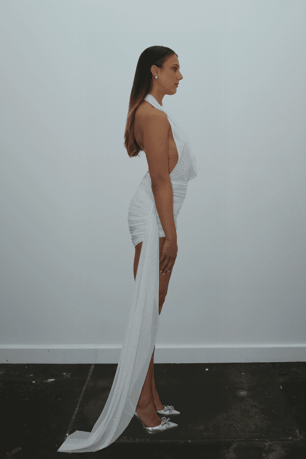 Tiffany Dress Ivory Glitter by DŽO – Trendy rhinestone-embellished sheer mesh mini with cowl neckline, ruched skirt, and dramatic side train, perfect for glamorous evening statement occasions.