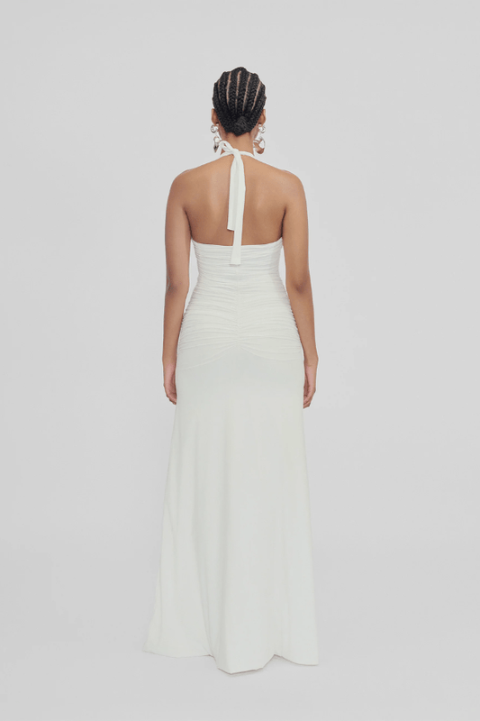 Roman Off White by Maygel Coronel – Elegant halter dress with deep V-neck, flattering ruching, and delicate 3D floral detail, perfect for refined events and celebrations.