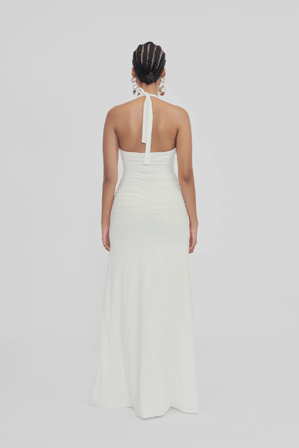 Roman Off White by Maygel Coronel – Elegant halter dress with deep V-neck, flattering ruching, and delicate 3D floral detail, perfect for refined events and celebrations.