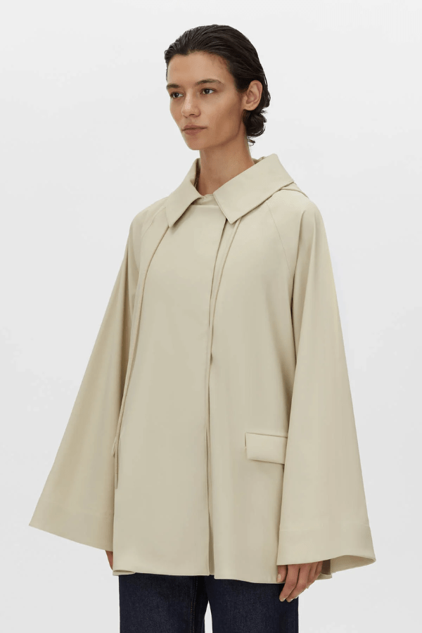 Memento Raincoat Alabaster by Camilla and Marc – double-breasted with hood and monogram detail, perfect for stylish rainy days or light layering.