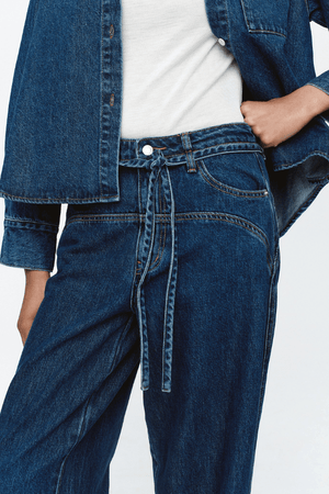 Tie Curve Seam Jean Heritage Blue by Marle, trendy mid-rise jeans with unique curved seam detailing and a relaxed, wide-leg fit. Perfect for a versatile, polished look with a detachable tie belt.