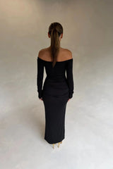 Black Haley off-shoulder midi dress with fitted bodice and flowy skirt, featuring short sleeves and a subtle slit.