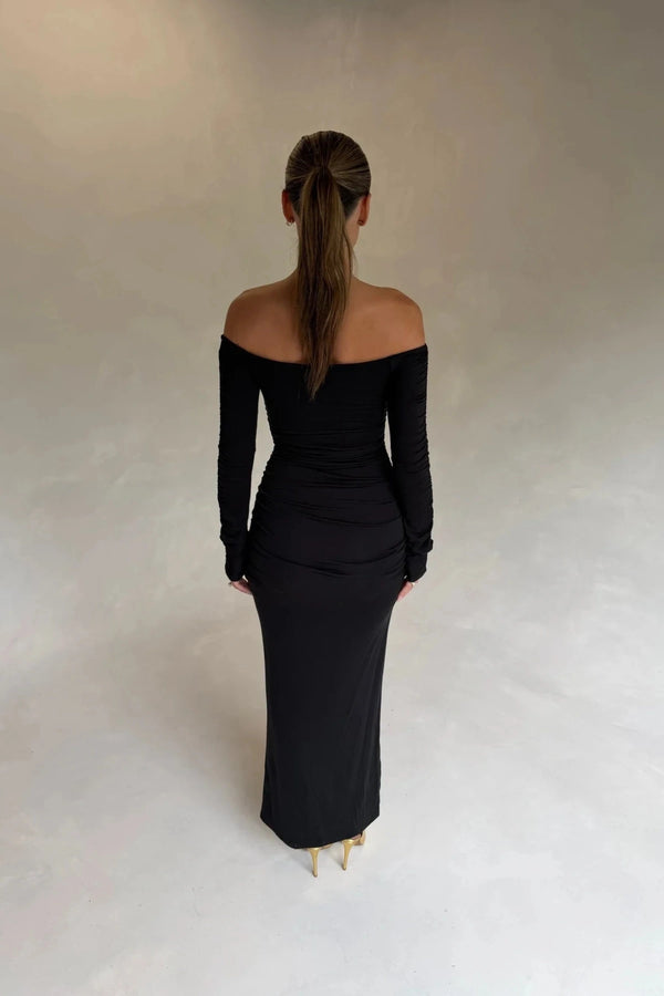 Black Haley off-shoulder midi dress with fitted bodice and flowy skirt, featuring short sleeves and a subtle slit.