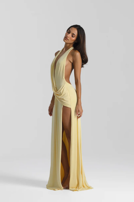 Winona Gown Lemon by Natalie Rolt, elongated halter neckline, asymmetric draped bust overlay, open back, exaggerated side split, gathered waterfall skirt, full-length hem, elevated jersey. Dry clean only.