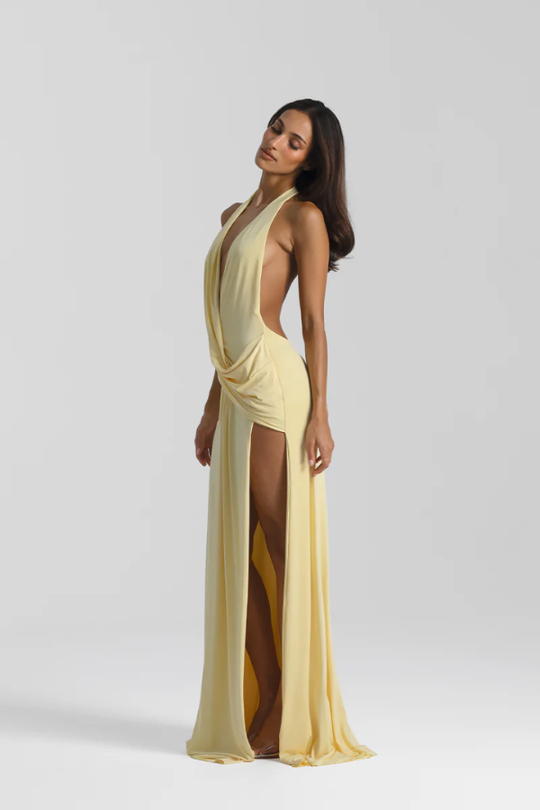Winona Gown Lemon by Natalie Rolt, elongated halter neckline, asymmetric draped bust overlay, open back, exaggerated side split, gathered waterfall skirt, full-length hem, elevated jersey. Dry clean only.