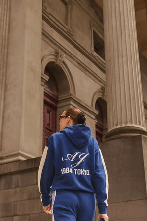 1986 Hoodie Estate Blue by Araminta James, soft cotton brushed fleece with contrast trim and velvet graphic, relaxed fit perfect for casual cool days.