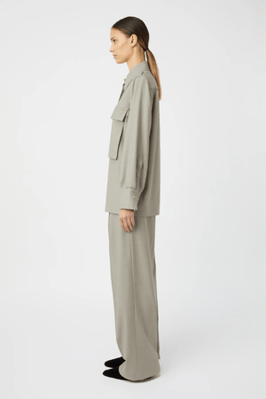 Drew Pant Mottled Stone by Camilla and Marc, tailored low-rise pant with front pleats, fishtail waistband, single arrow belt loops, and back jet pockets with button detail. Crafted in a wool-poly blend with permanent press finish.