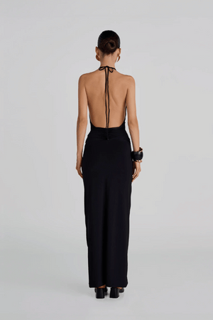 Lirio Maxi Dress Black by Maygel Coronel – A deep-V halter maxi with ruched waist, open back, and 3D floral detail for summer elegance.
