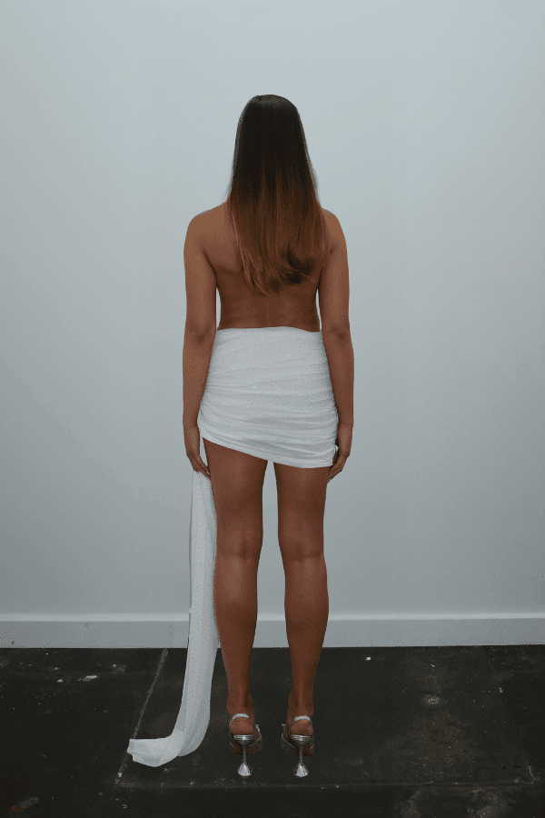 Tiffany Dress Ivory Glitter by DŽO – Trendy rhinestone-embellished sheer mesh mini with cowl neckline, ruched skirt, and dramatic side train, perfect for glamorous evening statement occasions.