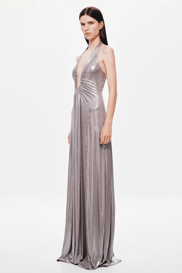 Jennifer Foil Jersey Dress Cinder by Misha – Trendy slim-fit maxi with deep V halter neckline, gathered waist, and cascading sash, perfect for glamorous day-to-evening occasions.