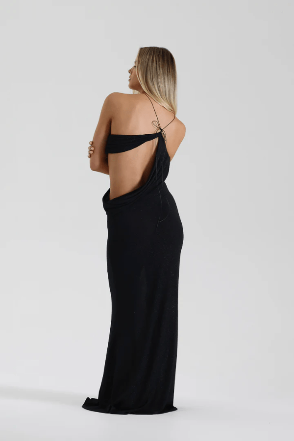 Elissa Dress Black by Natalie Rolt – A glamorous stretch-knit maxi with metallic threads, asymmetrical cutaway, and adjustable fit, perfect for elegant evenings and special occasions.