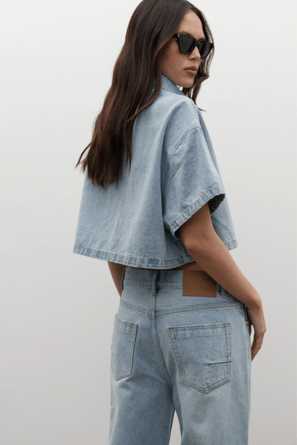 Zara Cropped Denim Shirt Oakland Blue by Bayse, a trendy cropped denim shirt with a relaxed fit and snap-button front. Perfect for effortless styling, whether paired with high-waisted denim or layered over a fitted tank.