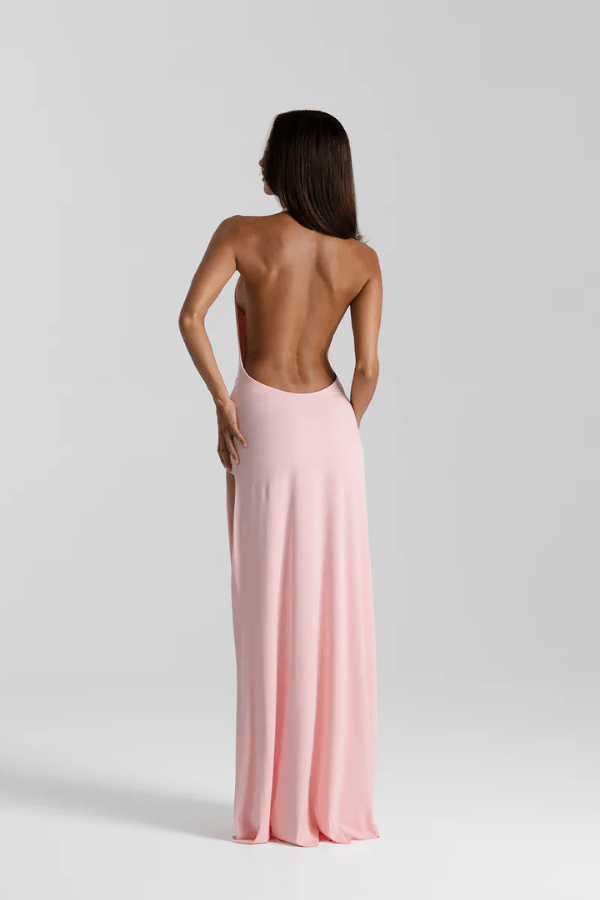 Winona Gown Blossom Pink by Natalie Rolt, elongated halter neckline, asymmetric draped bust overlay, open back, exaggerated side split, gathered waterfall skirt, full-length hem, elevated jersey. Dry clean only.