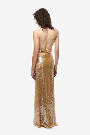 The Devon Sequin Dress by Misha, a mustard gold halter gown with cut-outs and ring detail. Perfect for parties, red carpets, or weddings.
