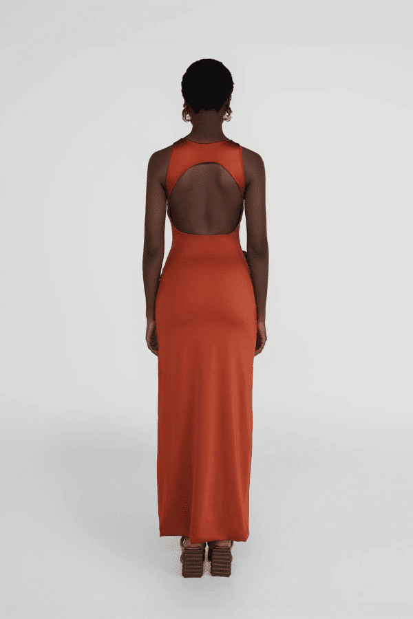 Tirso Terracotta by Maygel Coronel – Long dress with round neck, open back, ruched sash, and 3D flowers for elegant look.