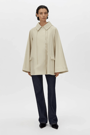 Memento Raincoat Alabaster by Camilla and Marc – double-breasted with hood and monogram detail, perfect for stylish rainy days or light layering.