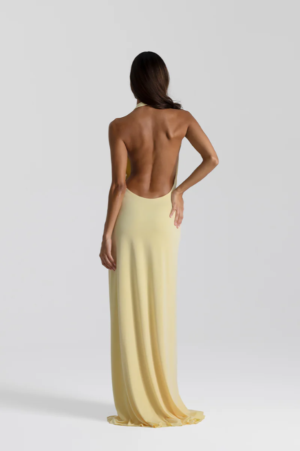 Winona Gown Lemon by Natalie Rolt, elongated halter neckline, asymmetric draped bust overlay, open back, exaggerated side split, gathered waterfall skirt, full-length hem, elevated jersey. Dry clean only.
