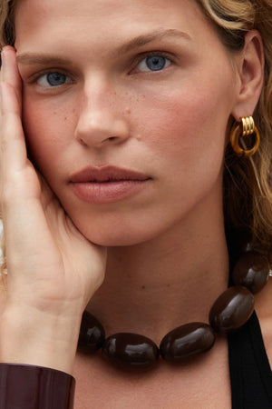 Luma Knot Earrings Gold/Tiger’s Eye by Heaven Mayhem, 18k gold PVD-plated knot earrings with natural Tiger’s Eye stone.