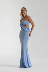 Elissa Dress Periwinkle by Natalie Rolt – A shimmering stretch-knit gown with metallic threads, asymmetrical cutaway, and flowing silhouette, perfect for sophisticated evening events and special occasions.