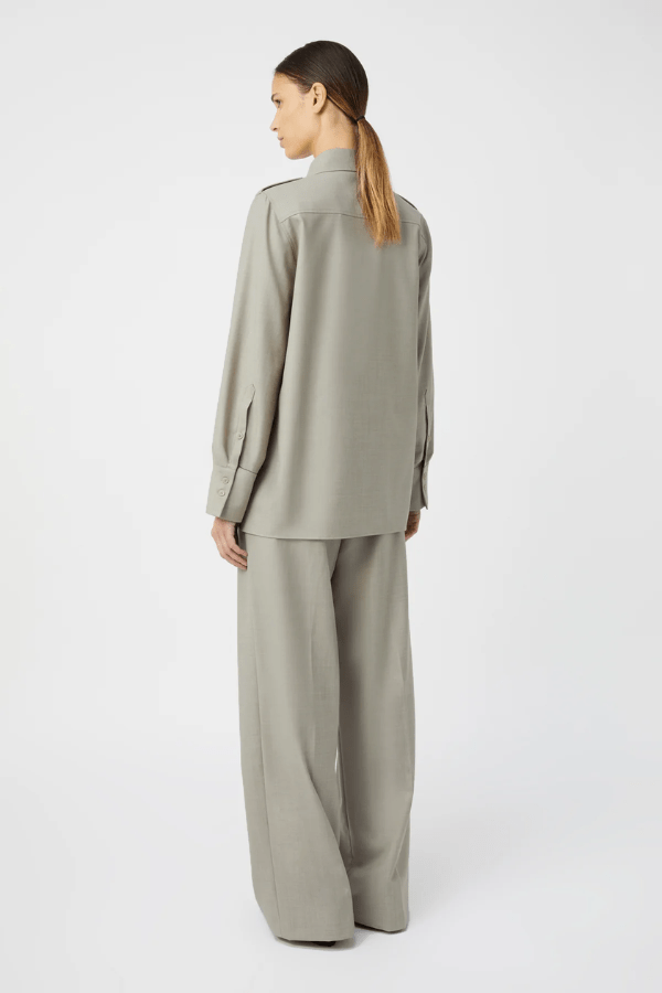 Drew Pant Mottled Stone by Camilla and Marc, tailored low-rise pant with front pleats, fishtail waistband, single arrow belt loops, and back jet pockets with button detail. Crafted in a wool-poly blend with permanent press finish.