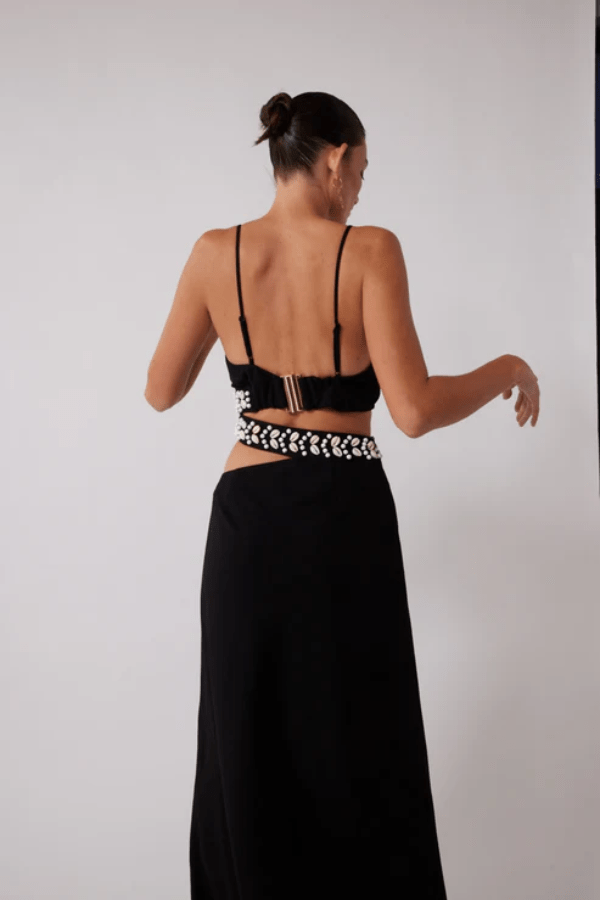 La Playa Maxi Dress Noir by The Wolf Gang – Maxi dress with cowrie shell cutouts, adjustable tie, and luxe gold clasp closure.