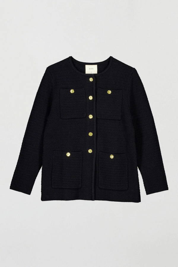 Helena Jacket Black by Onte – A stylish reinterpretation of the iconic Helena gilet, made from breathable 100% cotton yarn with a unique crochet-style stitch. Features a loose fit, gold Onte buttons, long sleeves, crew neck, and patch pockets.