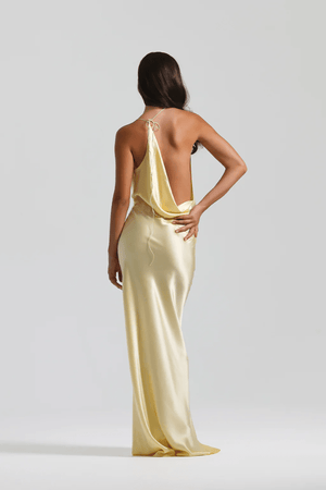 Gabi Gown Lemon by Natalie Rolt – A trendy bias-cut silk gown with an elegant asymmetric silhouette, open back, and delicate ties, perfect for special occasions.
