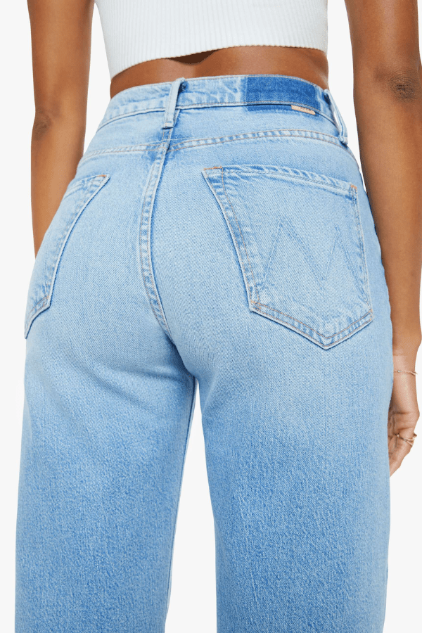The Lasso Sneak Sow Surreal by MOTHER, trendy super high-rise wide-leg jeans with a light blue wash, whiskering, and fading. Perfect for a vintage-inspired look with a clean hem and structured fit.