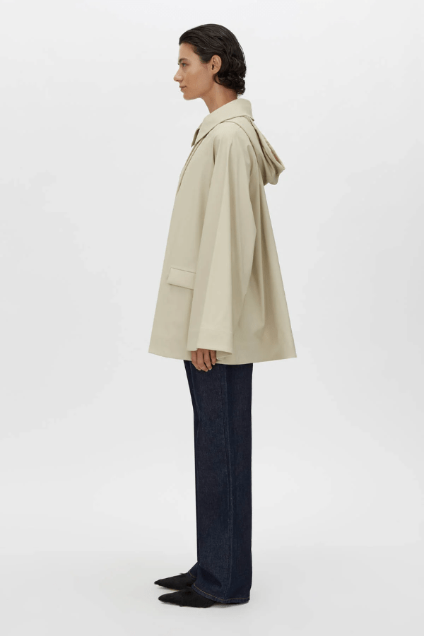 Memento Raincoat Alabaster by Camilla and Marc – double-breasted with hood and monogram detail, perfect for stylish rainy days or light layering.
