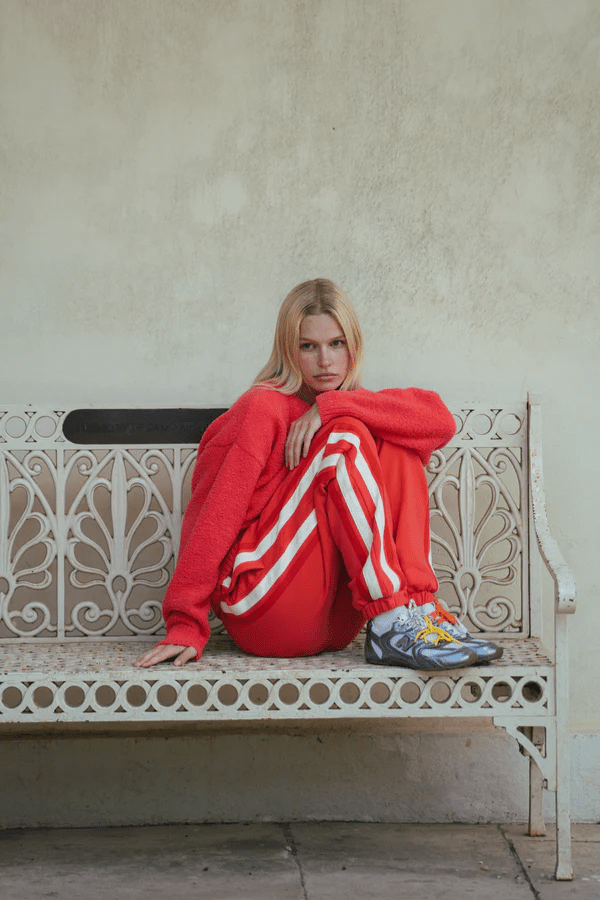 Bisous Trackpant Coral by Araminta James, features a relaxed fit with tapered leg, soft brushed fleece fabric, elasticized waistband with drawcord, side pockets, elastic cuffs, and contrast side trims.