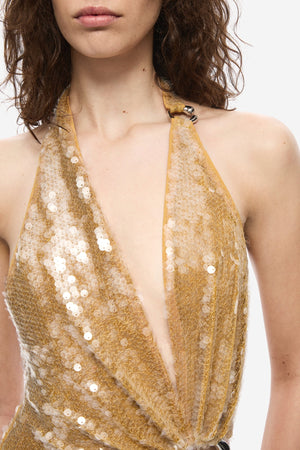 The Devon Sequin Dress by Misha, a mustard gold halter gown with cut-outs and ring detail. Perfect for parties, red carpets, or weddings.