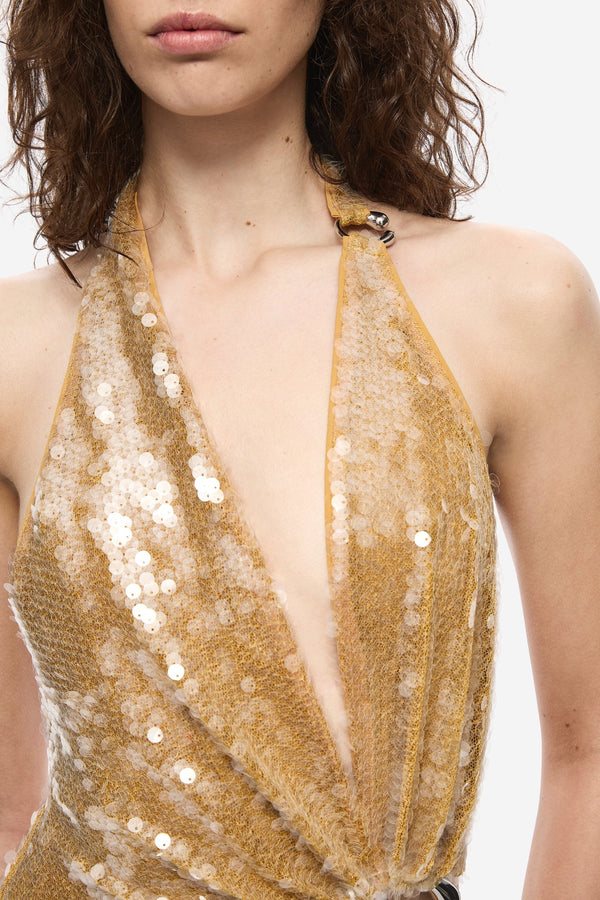 The Devon Sequin Dress by Misha, a mustard gold halter gown with cut-outs and ring detail. Perfect for parties, red carpets, or weddings.